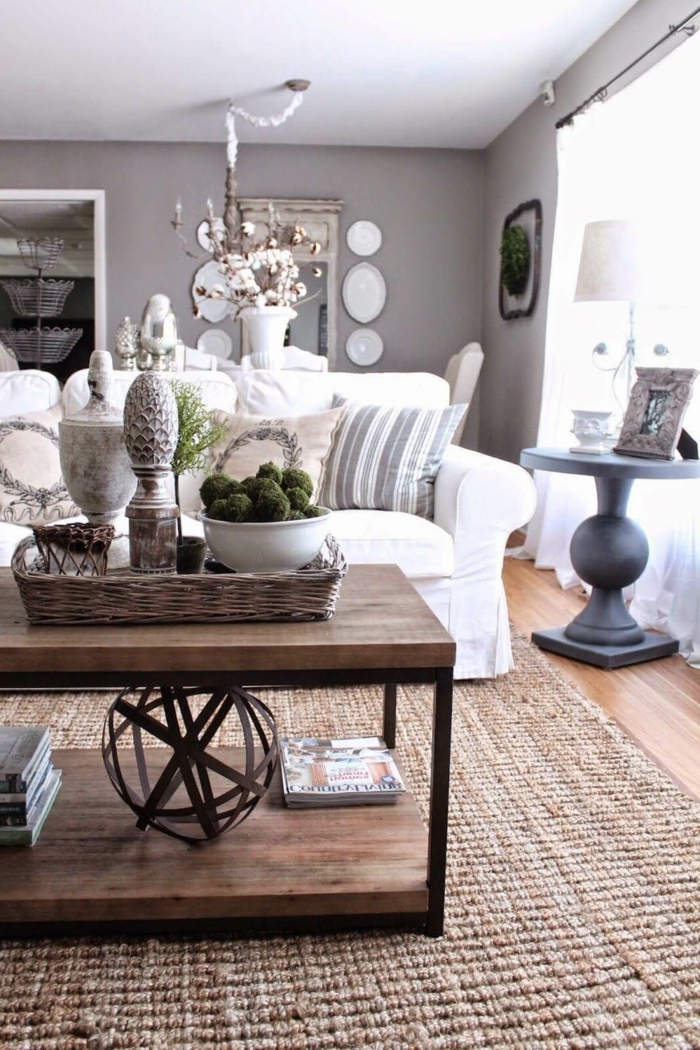 table industrielle, murs gris, tapis fibre naturel, table basse ronde, sofa blanc et coussins, plateau rustique