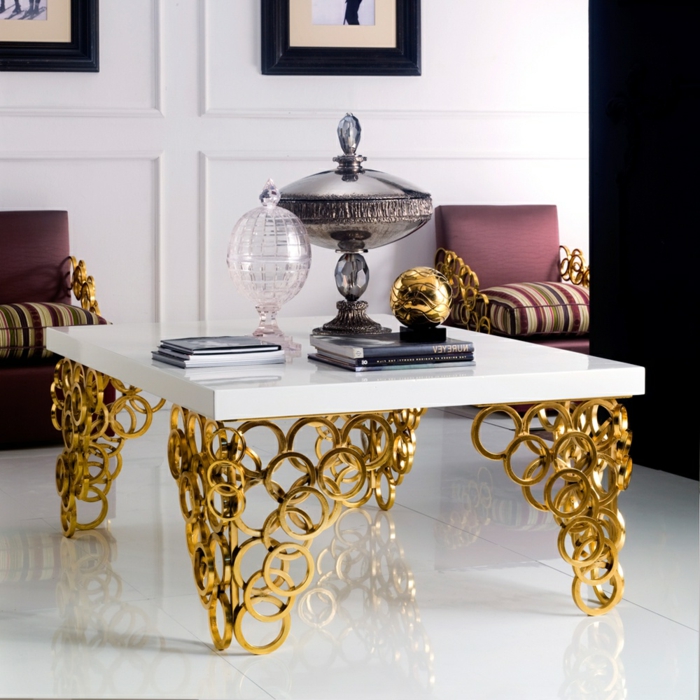 salon de luxe, piétement doré, plateau blanc, décoration avec bonbonnière en cristal, tas de magazines, fauteuils vintage