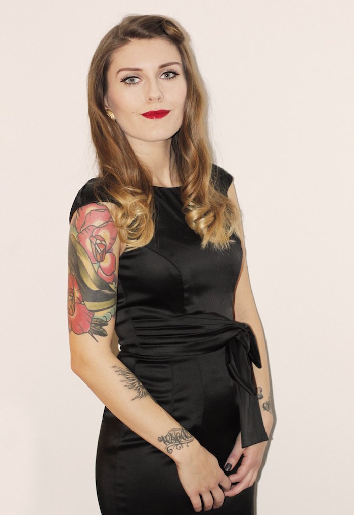 tenue de soirée femme avec robe noire sur theme pin up des années 50 avec maquillage retro et tatouage sur le bras et poinget