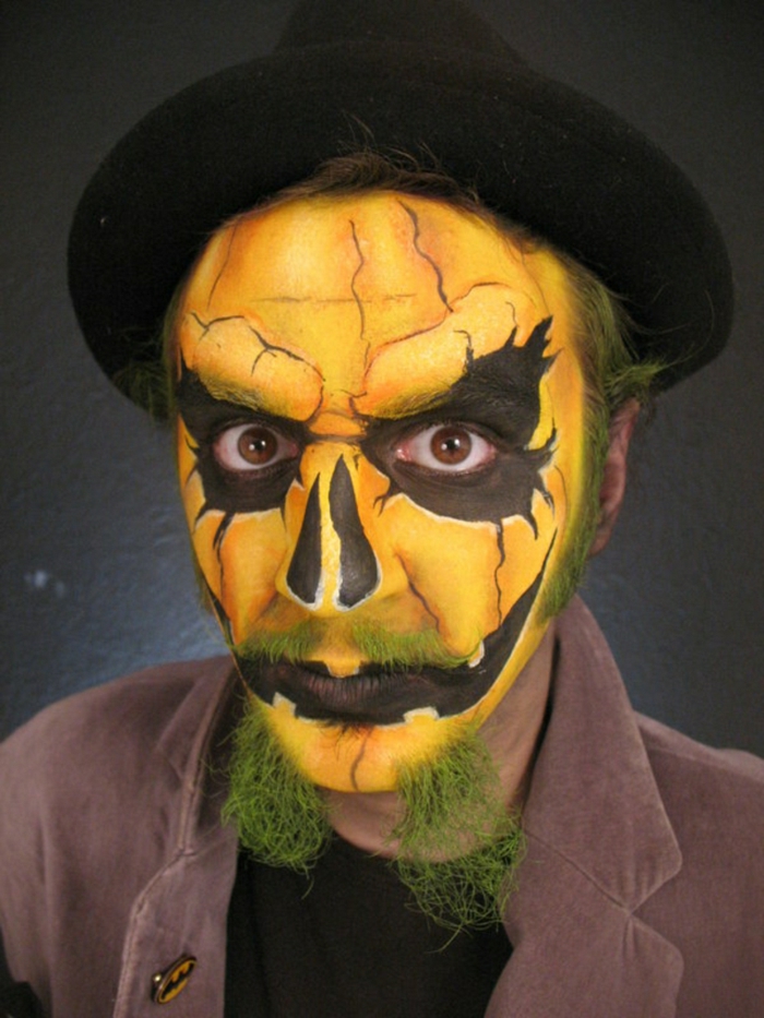 maquillage homme citrouille, moustache verte, lèvres noires, grandes ombres en noir foncé autour des yeux, chapeau