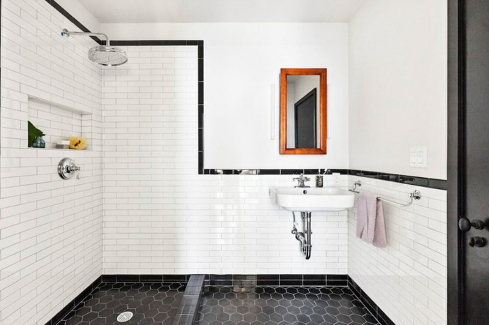 petite salle de bain coquette, sol en carreaux géométriques noirs, lavabo suspendu, tuyauterie apparente, miroir cadre en bois