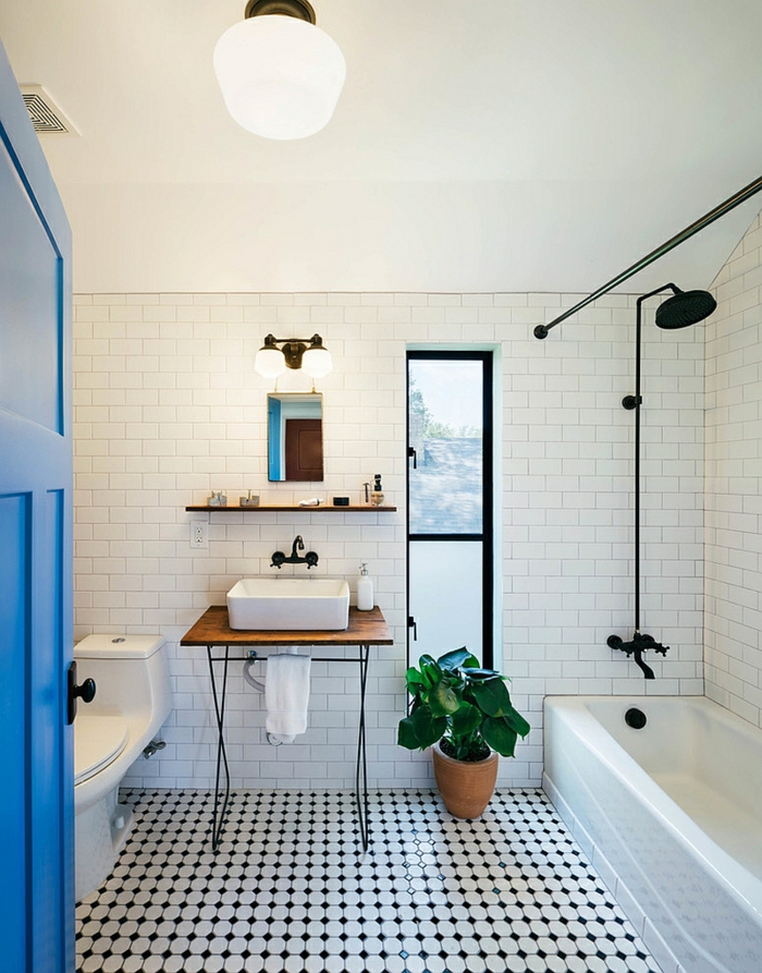 carrelage vintage noir et blanc, pot de fleur, baignoire rectangulaire, carreaux métro, meuble sous vasque recyclé en bois, porte bleue