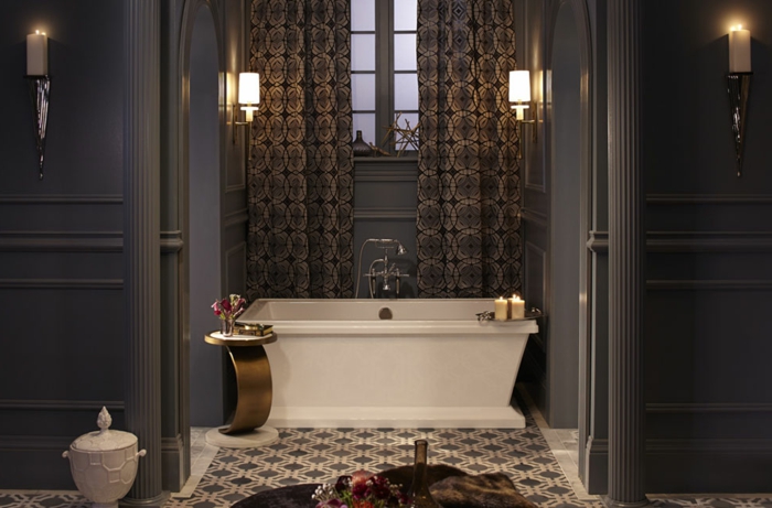 salle de bain gris et blanc, carreaux de ciment, baignoire blanche aux lignes droites, petit tabouret métallique, murs gris, rideaux lourds motifs géométriques