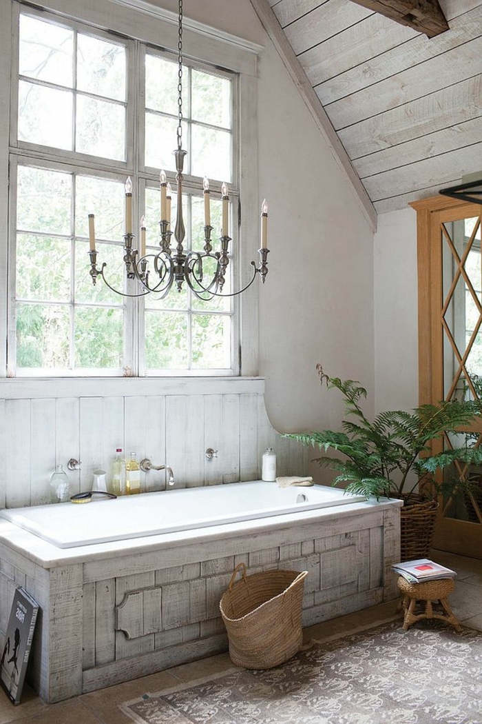 baignoire blanche rectangulaire, grand chandelier vintage, plafond de salle de bain sous pente, plante verte