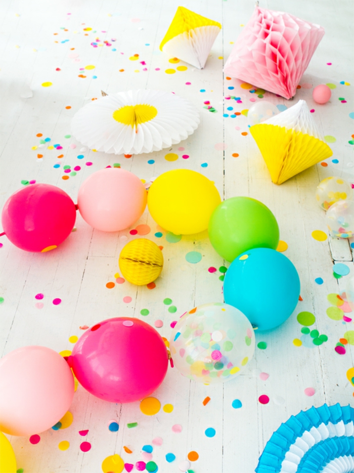 chaîne de ballons en couleurs vives, pinatas de papier décoratif, confettis sur un plancher en planches blanches