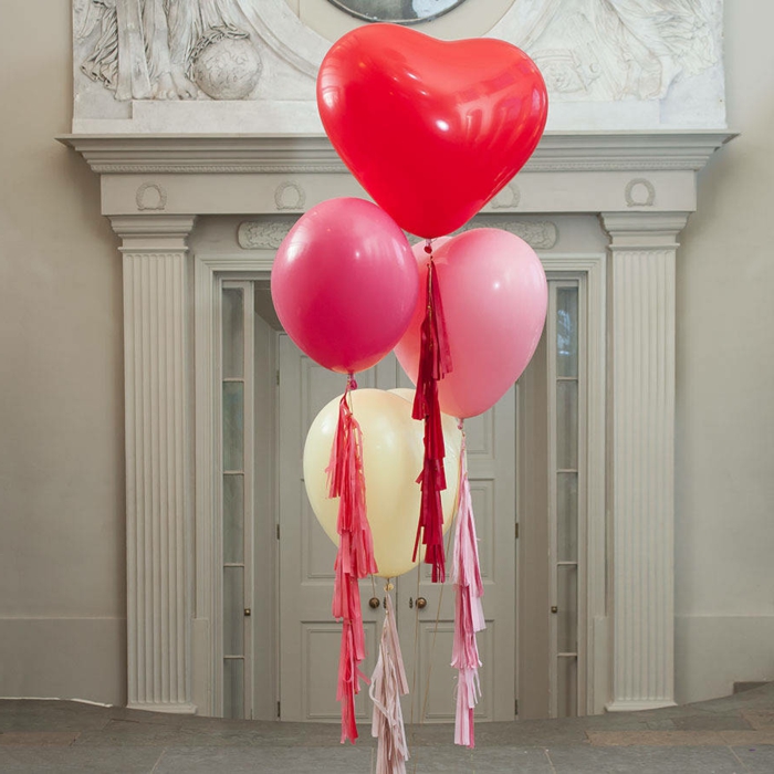 ballons en forme de coeurs liés qui flottent en l'air près d'une grande porte blanche, franges décoratives