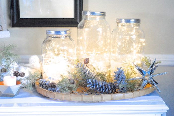 exemple de décoration de noel à fabriquer pour adultes, bocal en verre avec guirlande lumineuse, composition décorative en branches et pommes de pin