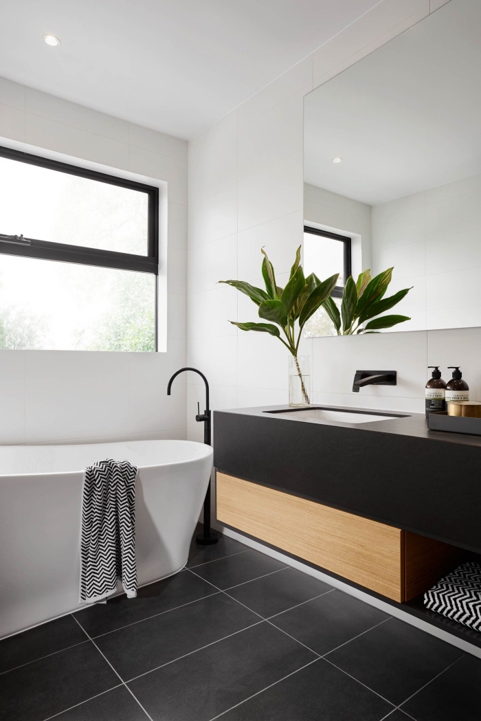 design stylé dans une salle de bain moderne aux murs blancs avec carrelage de sol en noir et meuble sous vasque en noir et bois