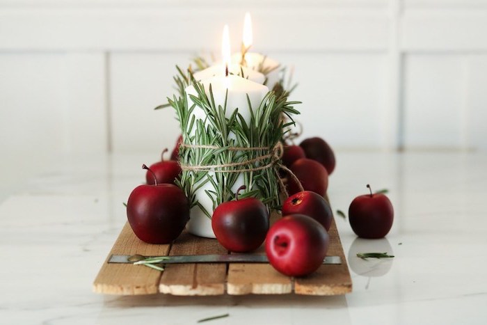idee originale deco centre de table noel en planches bois rustique avec bougies enveloppées de romarin et deco de pommes de pin rouges, centre de table noël fait maison