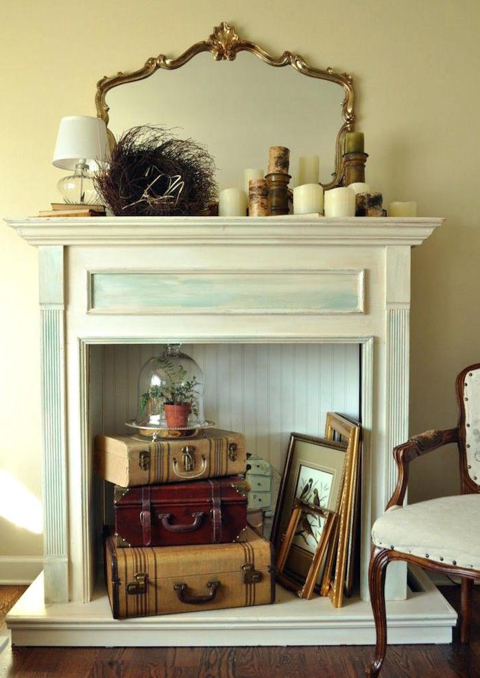meuble imitation cheminée en bois nblanc bleu patine pour décoration retro avec vieilles valises vintage cadres et bougies