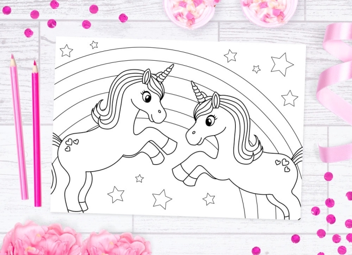 un coloriage de licorne à imprimée avec deux petites licorne jouant ensemble devant un arc-en-ciel