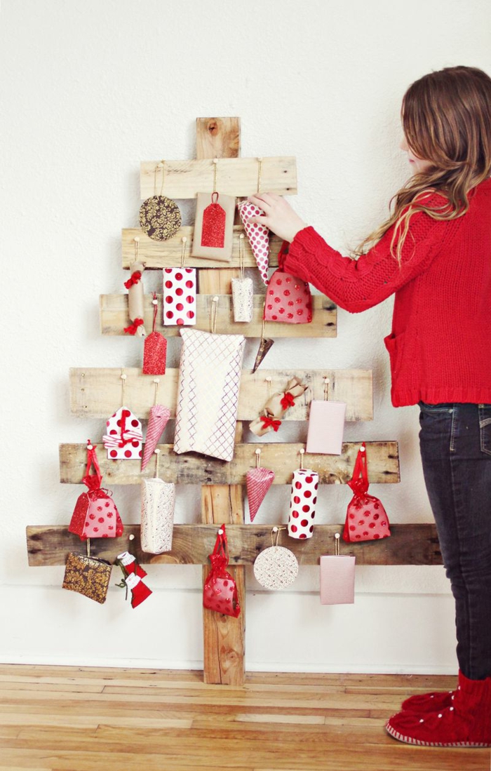 sapin en bois faits avec des planches croisées, ornements et cadeaux enrobés de papier décoratif rouge et blanc, cadeaux blancs à pois rouges