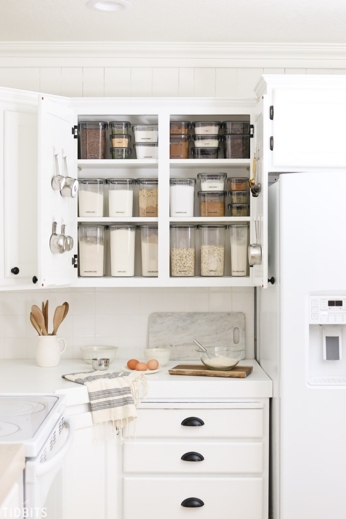 rangement placard cuisine avec des boîtes de conservation à couvercle hermétique pour aliments et des crochets fixés aux portes du placard