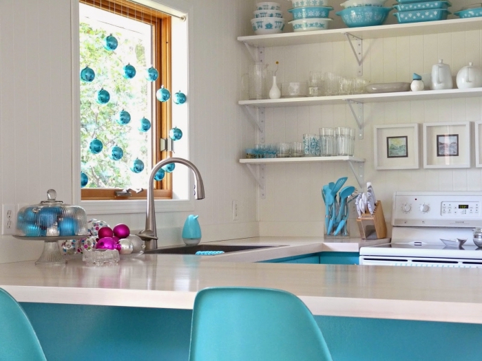 une suspension de boules de noël en bleu turquoise suspendue à la fenêtre qui s'harmonise avec les couleurs de la cuisine