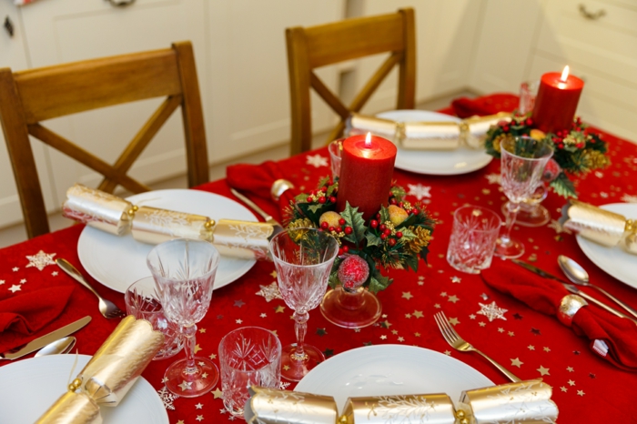 décoration de Noel en rouge et blanc, surprises dorés dans les assiettes en porcelaine, verres en cristal
