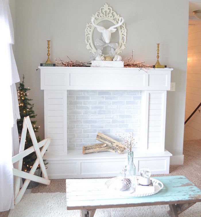 meuble imitation cheminée blanc pour décoration de salon cosy sur mur gris et sol moquette avec petite table en bois patine retro