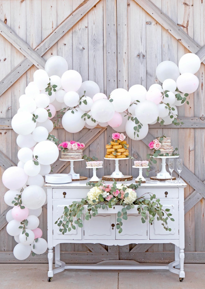 arche de ballons blancs, feuilles vertes, présentoir à gâteau, arche mariage blanche, gâteau et donuts
