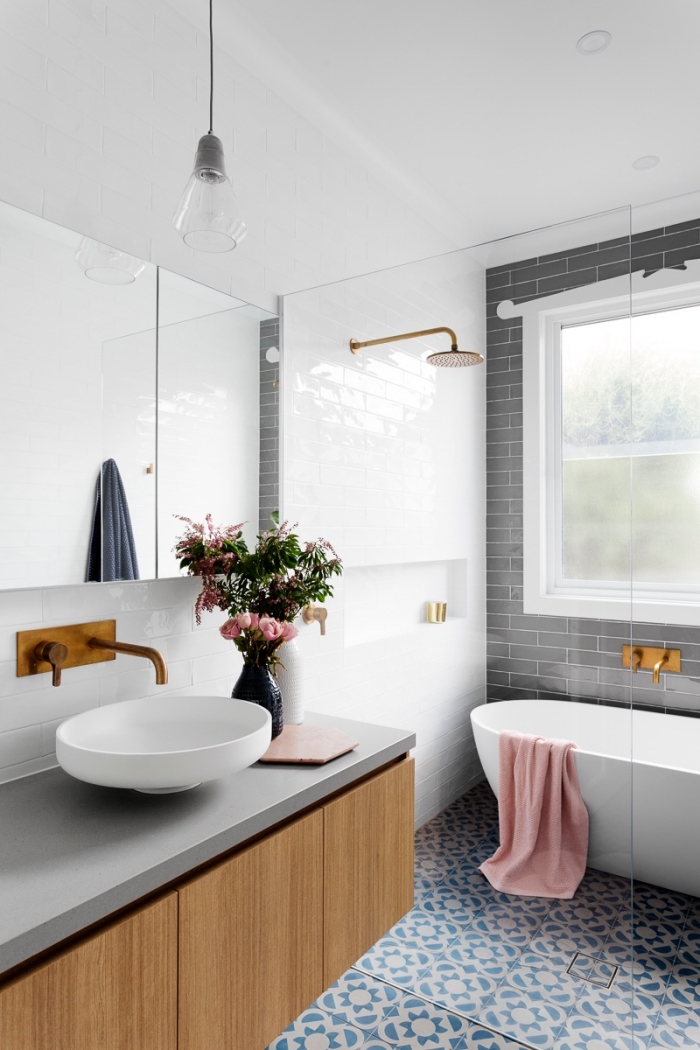 intérieur moderne dans une salle de bain aux murs blancs avec mur en carreaux briques grises et accents en or