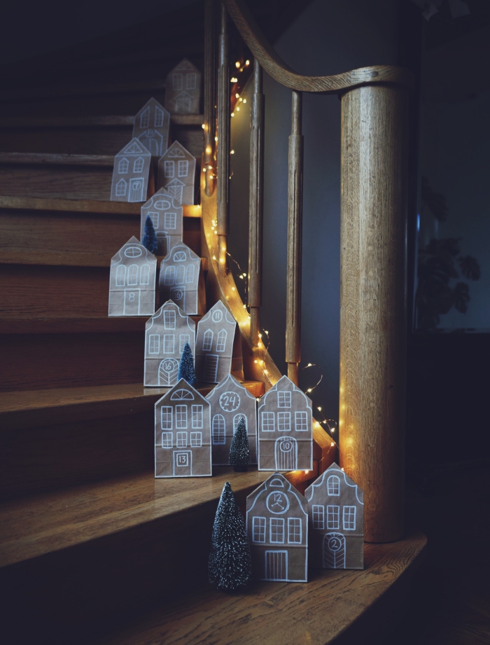 des maisons de noël en pochettes kraft recyclées, posées sur les marches de l'escalier tout au long des rampes en bois, décoration de noël à fabriquer en papier de récupération