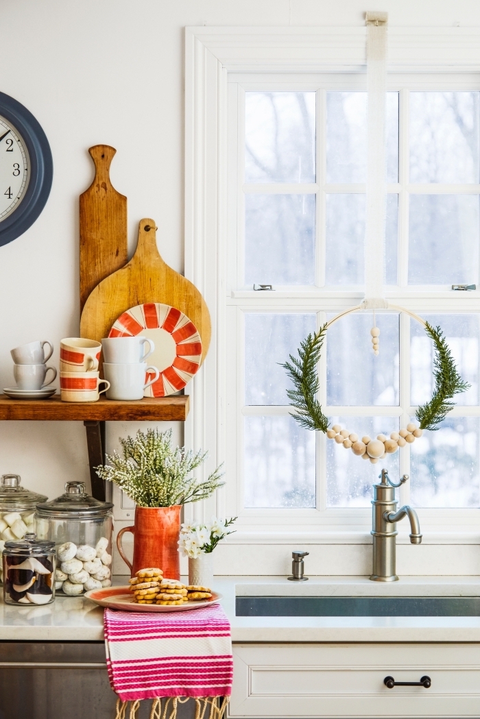 décoration de cuisine pour noël avec une simple couronne réalisée en cerceau de bois, perles de bois et quelques brins de sapin, suspendue à la fenêtre derrière l'évier