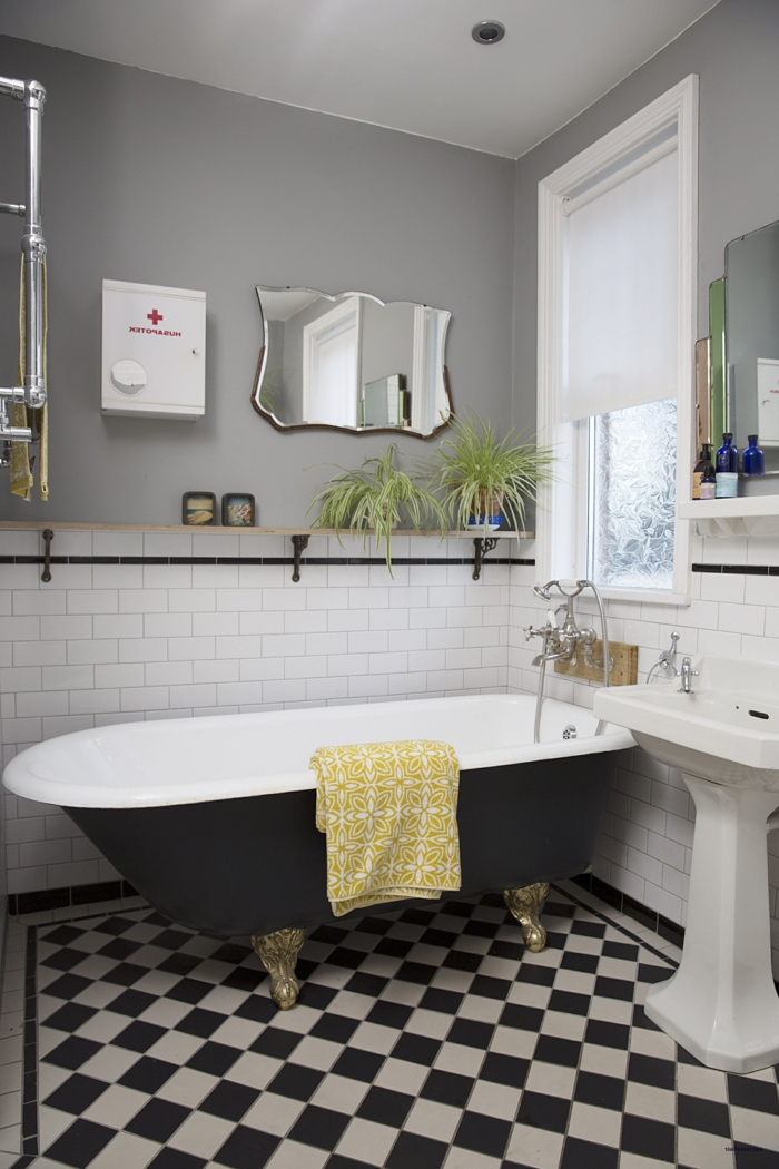 salle de bain noire et blanche, baignoire en fonte, carrelage damier, miroir art déco, vasque sur pied antique, mur gris