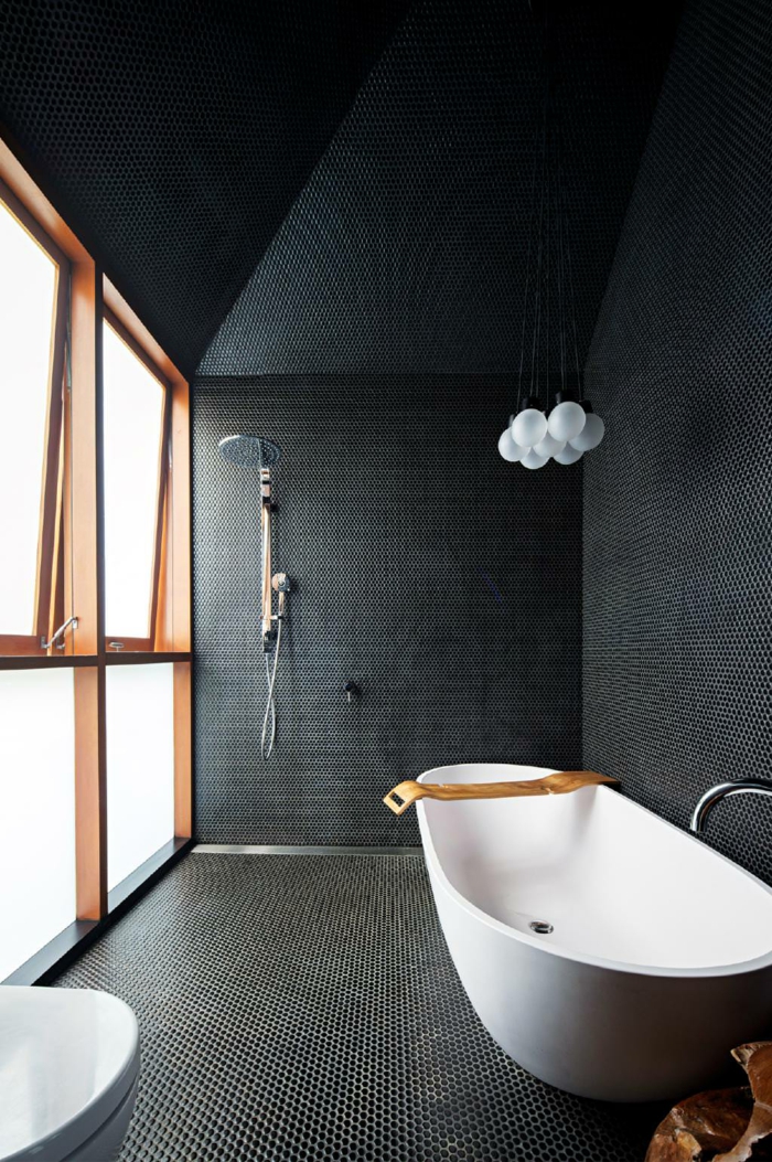 salle de bains grise, fenêtre cadres de bois, sol en petites tuiles, baignoire îlot et lavabo blancs