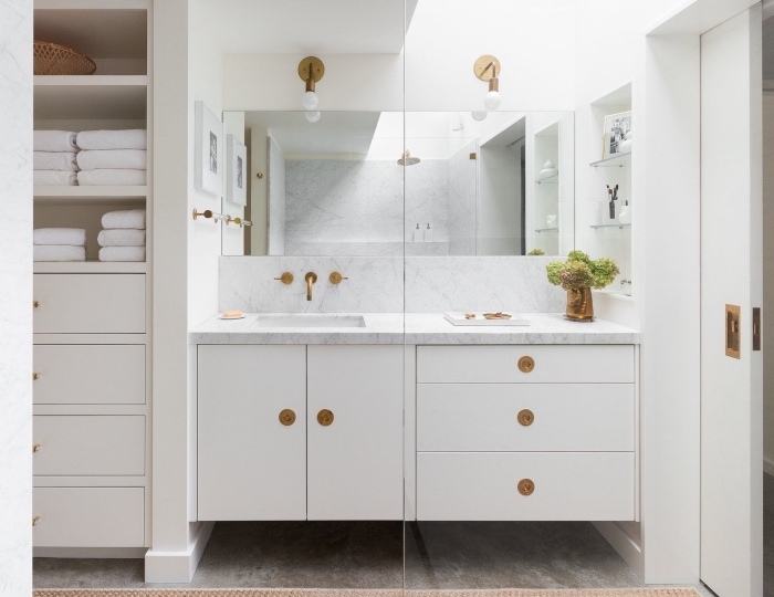 meuble salle de bain moderne avec armoires et tiroirs blancs à poignées dorées, déco stylée en marbre et or