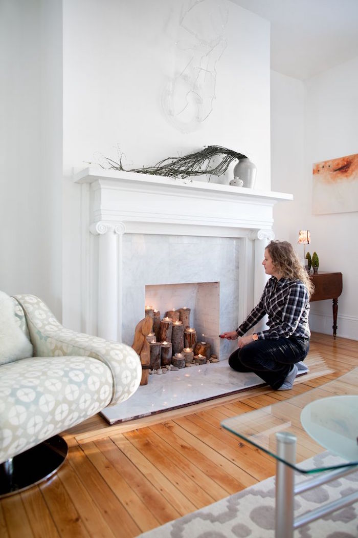 faux manteau de cheminée condamnée avec mini biches bougies dans foyer marbre dans salon blanc scandinave sur sol en parquet 
