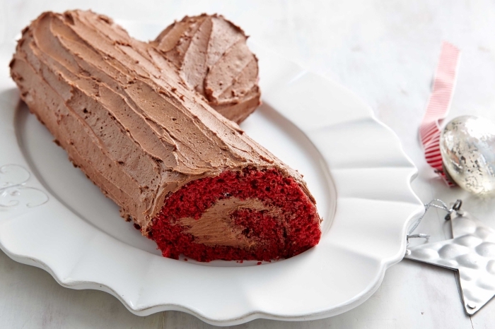 gâteau red velvet cake en forme de bûche de noël originale au glaçage chocolat servie dans une assiette dentelée