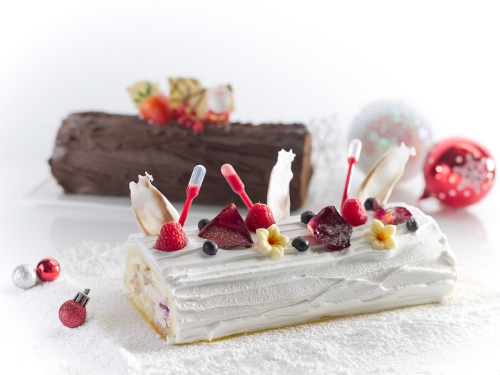 deux versions du gâteau roulé traditionnel, recette de buche de noel au chocolat ou à la vanille décorée avec des fruits rouges et des fleurs comestibles