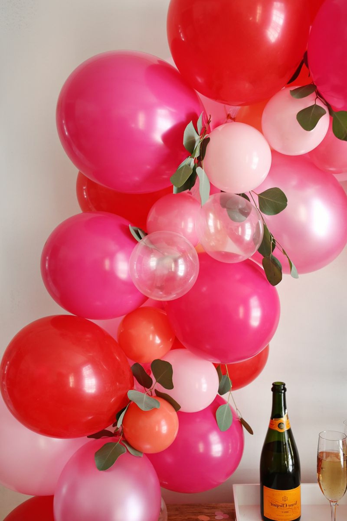 grands ballons cyclamen et petits ballons roses et transparents, feuilles décoratifs, bouteille de champagne et verre