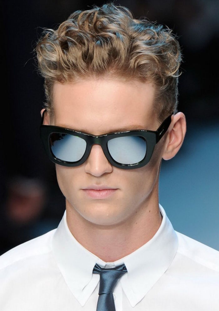 homme blond aux cheveux bouclés avec dégradé et dessus plus long et lunettes de soleil et chemise blanche