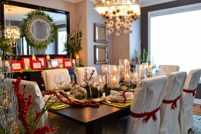 grande table en bois foncé, chaises blanches, grand miroir rectangulaire au cadre foncé, grands porte-bougies, sous-assiettes verts