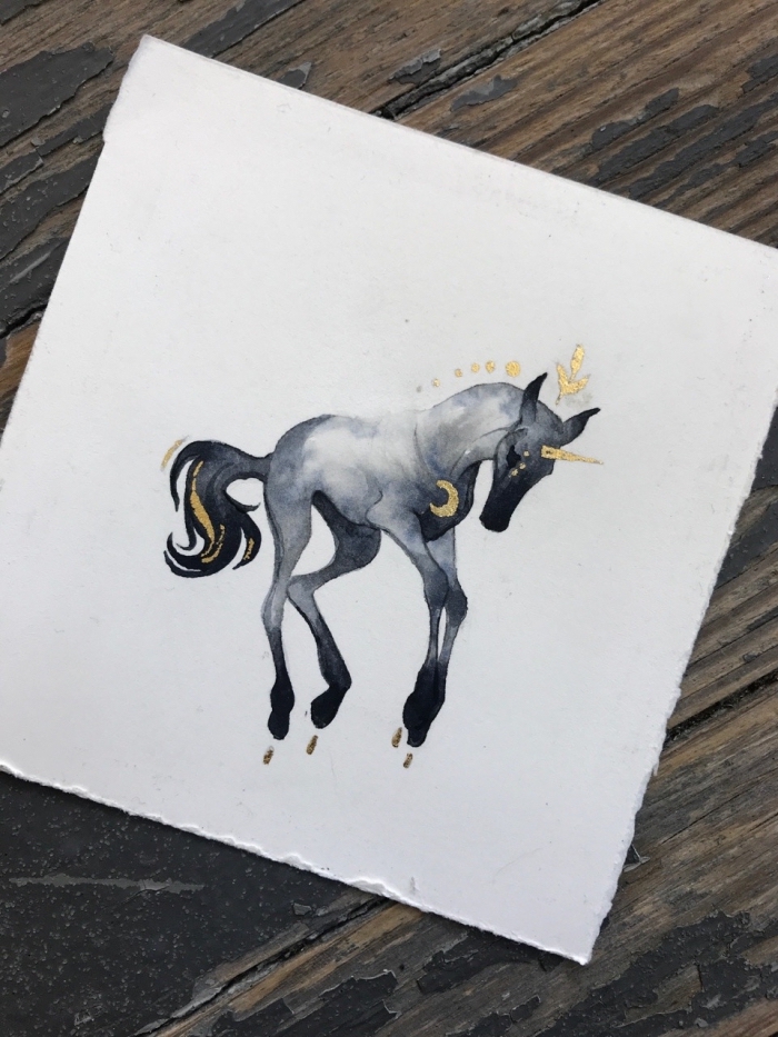 dessin de licorne facile et originale coloré à l'aquarelle en nuances de gris, parsemée d'or, dessin de créature de fantaisie qui semble flotter dans l'air