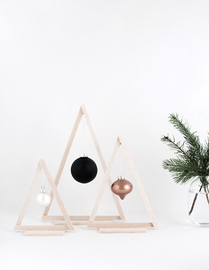 des triangles en bois transformés en sapins décoratifs graphiques et minimaliste avec une suspension de boule de noel