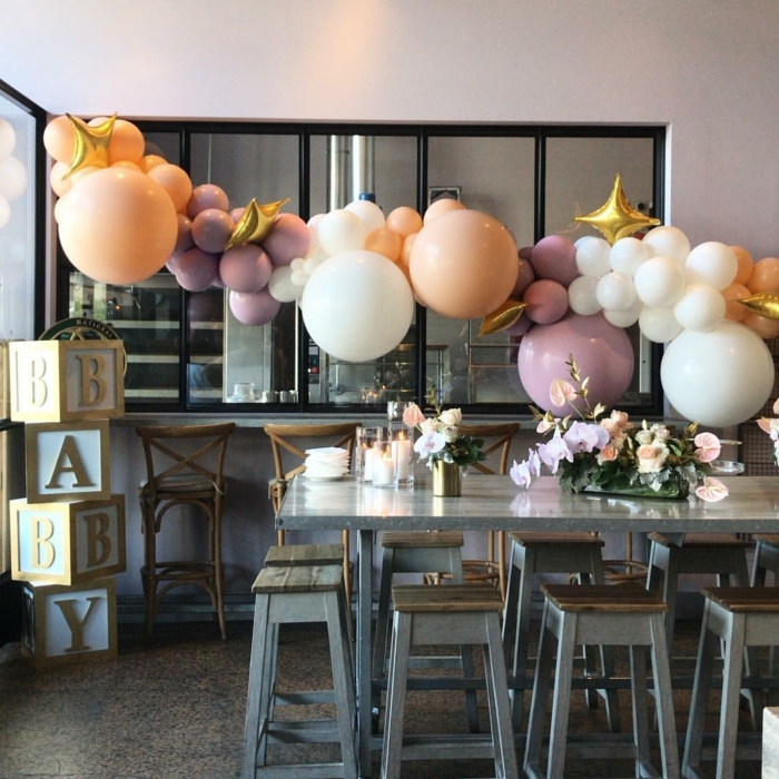 suspension de ballons mauves, oranges et blancs, longue table grise, tabourets gris et bois, chaises de bar vintage