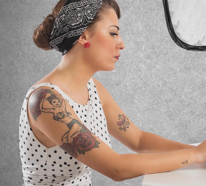 tatouage bras pour femme avec look pin up année 50 avec robe à pois et bandana noir dans les cheveux et tattoo ancre noeud sur manche
