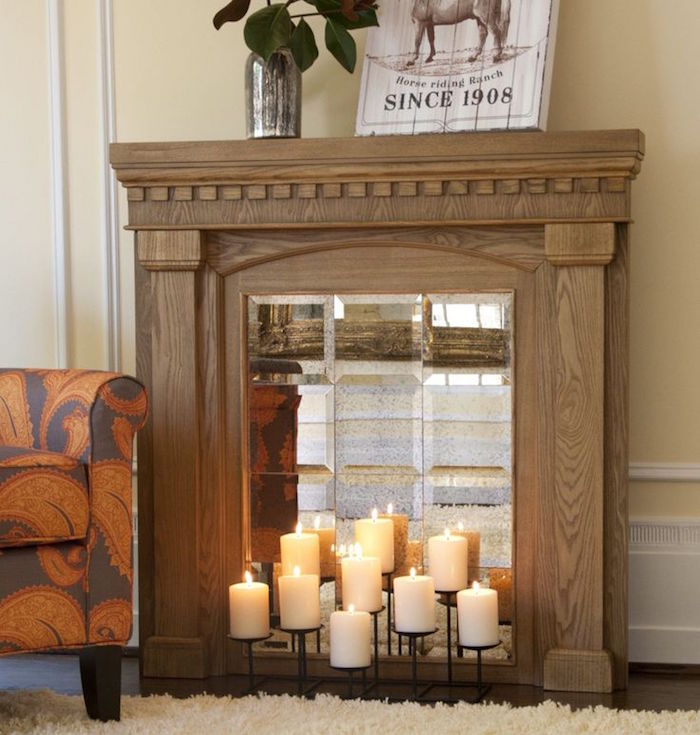 meuble en bois imitation cheminée avec faux insert miroir et bougies pour déco murale salon avec moquette et canapé orange marron