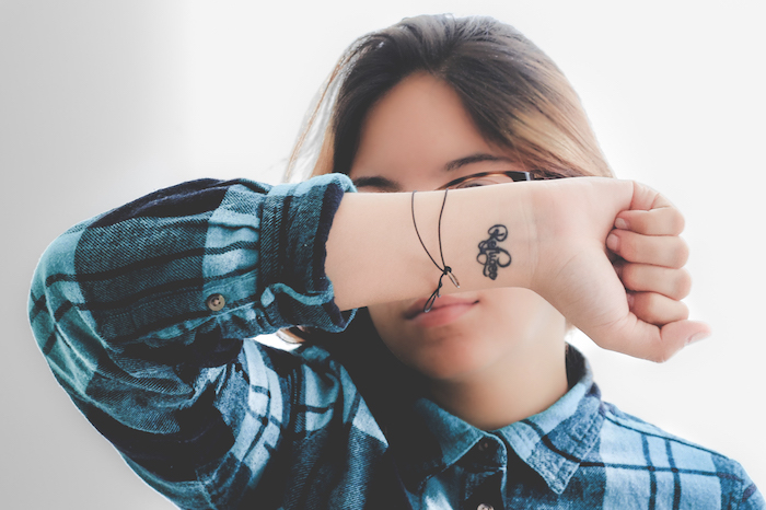 mini tattoo discret sur le poignet pour femme avec chemise à carreaux bleue
