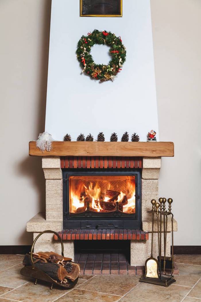 idée de cheminée traditionnelle design à foyer fermé pour maximiser la chaleur, deco couronne de noel, pommes de pin