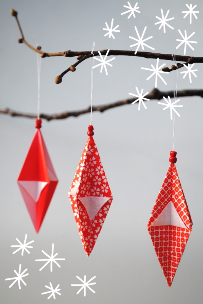 pliages origami ornements de noël géométriques en papier imprimé à motifs rouge et blanc, suspendus à une branche décorative