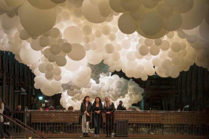installation à Covent Garden, grandes suspensions de grappes de ballons blancs au plafond du bâtiment et spectateurs