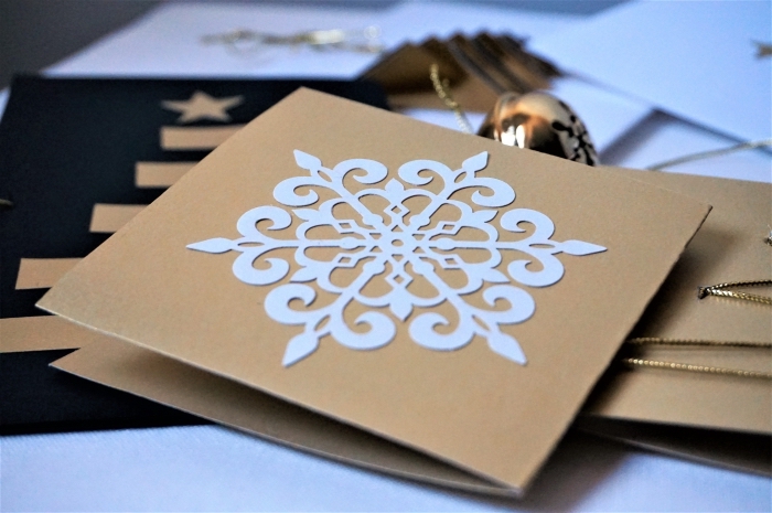 jolie carte noel à réaliser avec papier kraft brun, modèle de flocons de neige à découpé de papier cartonné blanc