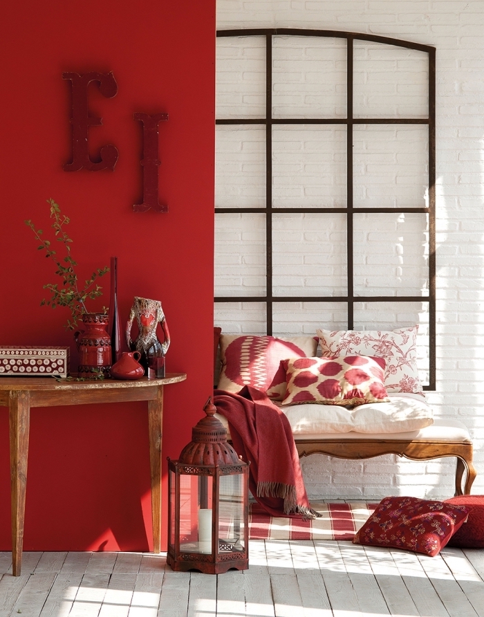deco chambre femme aux murs rouges, design intérieur de style ethnique chic avec objets en bois, coin cozy avec coussins et tapis en blanc et rouge