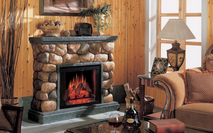 fausse cheminée en fausses pierres avec faux feu electrique ecran dans salon avec décoration type chalet avec mur en bois et meubles anciens