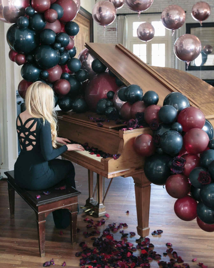 piano en bois, banquette en bois, guirlande de ballons foncés, ballons mauves suspendus en l'air