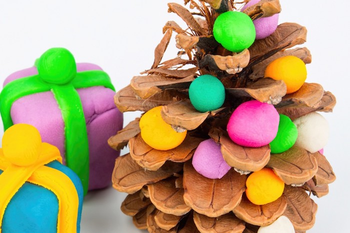 pomme de pin décorée de boules de pate fimo colorées et de petites figurines de cadeaux en pate fimo, deco noel simple a fabriquer