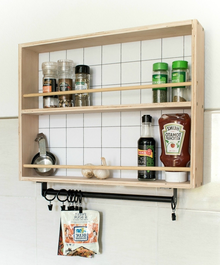 une étagère ouverte à encadrement d'aspect vintage avec une barre à crochets en acier noir qui sert de rangement à épices 