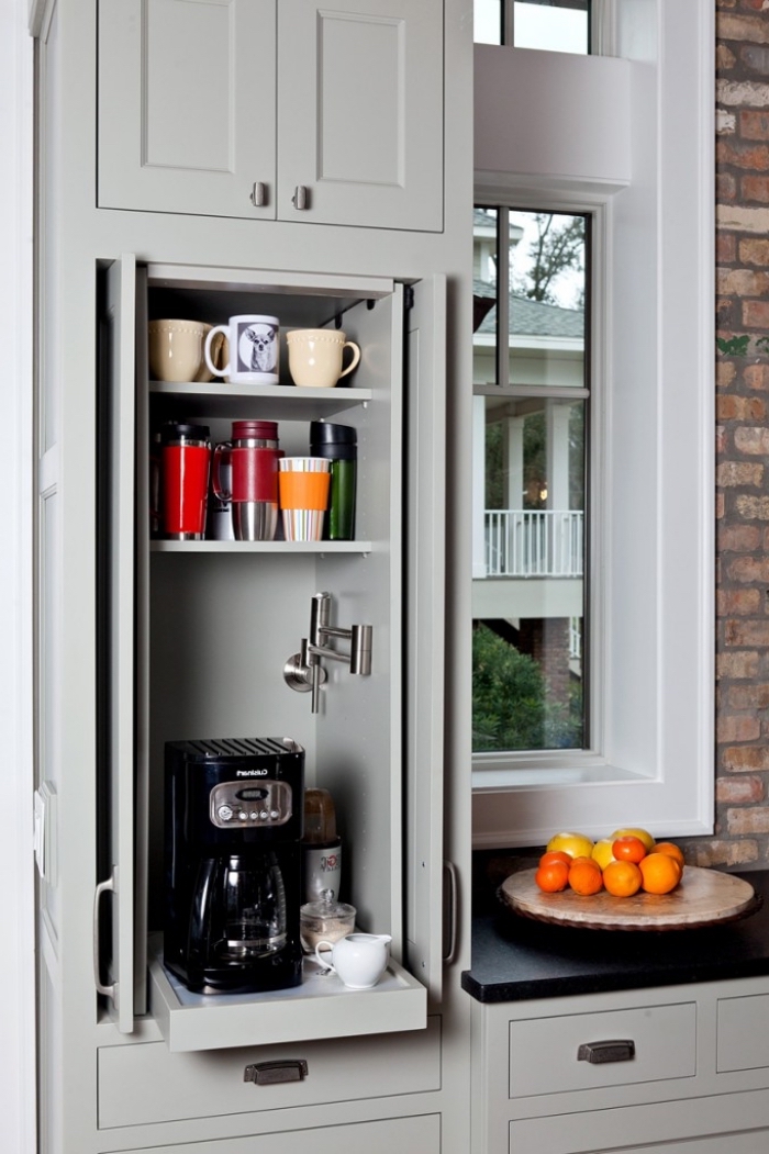 un coin café aménagé dans le placard de cuisine avec des étagères pour les tasses à café et une tablette coulissante pour la machine à café