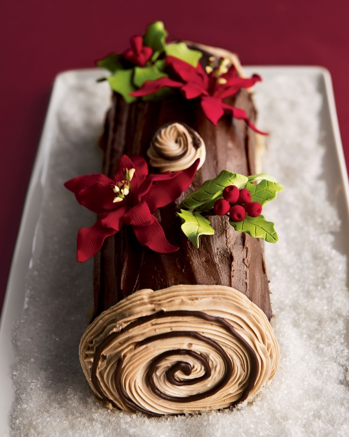 une buche patissiere facile au chocolat, décorée avec des étoiles de noël et des feuilles de houx en pâte à sucre